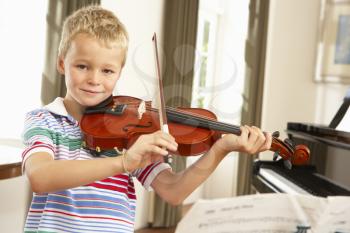 Young boy playing violin at home