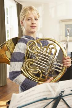 Girl holding French horn at home