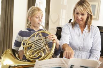 Girl playing French horn in music lesson