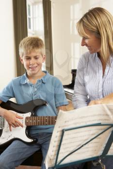 Boy playing electric guitar in music lesson
