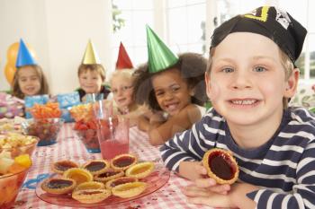 Young children eating jam tarts at birthday party