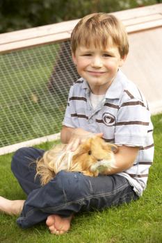 Young boy in garden holding guinea pig