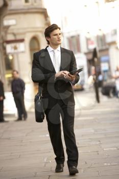Businessman with tablet walking down street