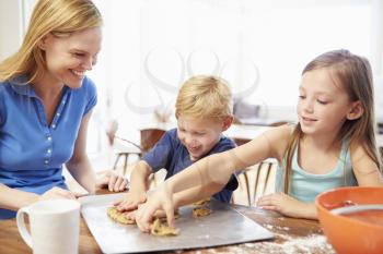 Mother And Children Baking Cookies Together At Home