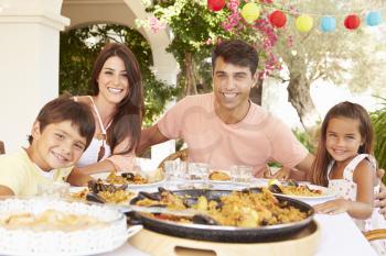 Hispanic Family Enjoying Outdoor Meal At Home Together