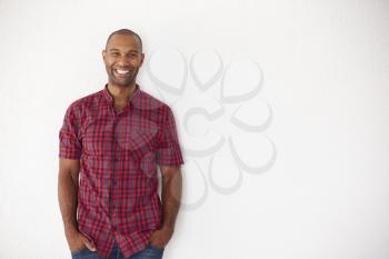 Portrait Of Casually Dressed Man Leaning Against White Wall
