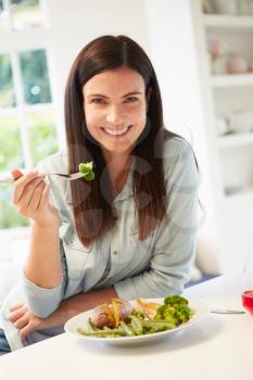Portrait Of Woman Eating Healthy Meal In Kitchen