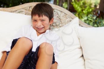 Smiling Hispanic Boy At Home Sitting On Outdoor Seat