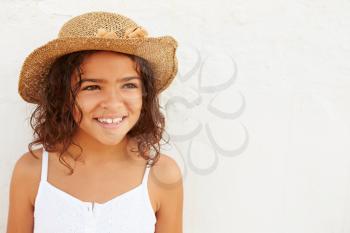 Smiling Young Girl Wearing Hat Standing Against White Wall
