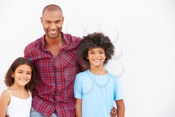 Father And Children Standing Outdoors Against White Wall