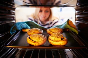 Woman Putting Stuffed Mushrooms Into Oven To Cook