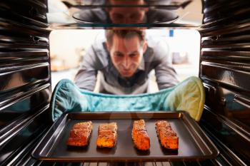 Man Taking Cooked Tray Of Salmon Fillets Out Of The Oven