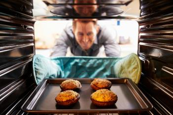 Man Taking Cooked Tray Of Stuffed Mushrooms Out Of The Oven