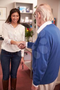 Receptionist Greeting Senior Male Patient At Hearing Clinic