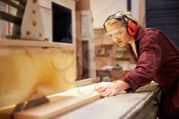 Female Apprentice Using Circular Saw In Carpentry Workshop
