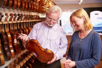 Salesman Advising Customer Buying Violin