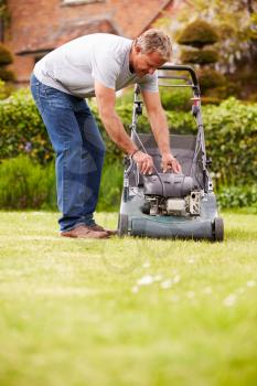 Man Working In Garden Cutting Grass With Lawn Mower