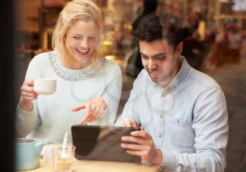 Couple Viewed Through Window Of Caf Using Digital Tablet