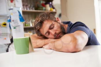Tired Man Asleep At Kitchen Table Next To Mobile Phone