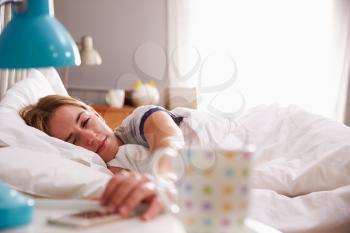 Sleeping Woman Being Woken By Mobile Phone In Bedroom