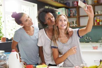 Three Female Friends Taking Selfie Whilst Making Breakfast