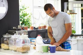 Young Man Wearing Pajamas Preparing Breakfast In Kitchen