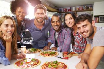 Group Of Friends Making Pizza In Kitchen Together