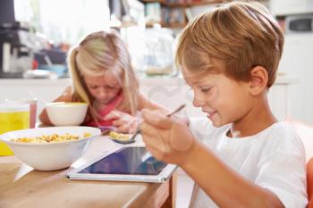 Children Eating Breakfast Whilst Using Digital Tablet
