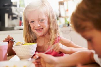Portrait Of Children Eating Breakfast At Kitchen Table