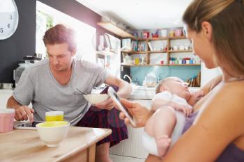 Family With Baby Girl Use Digital Devices At Breakfast Table