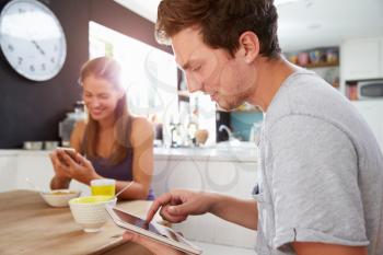 Couple Eating Breakfast Using Digital Tablet And Phone