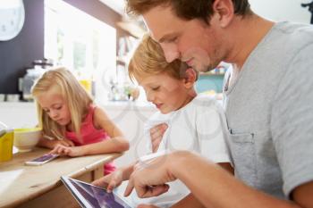 Father And Children Using Digital Devices At Breakfast Table
