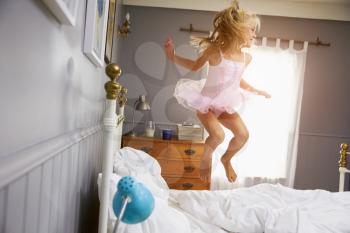 Girl In Ballerina Outfit Jumping On Parents Bed
