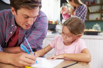 Father Helping Daughter To Draw Picture At Kitchen Table