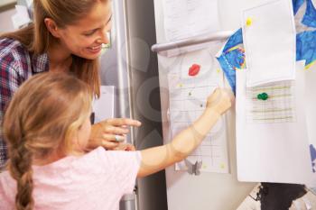 Mother And Daughter Putting Star On Reward Chart