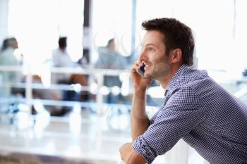 Portrait of man talking on phone, office interior