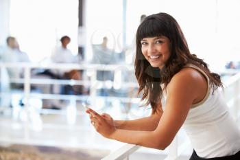 Portrait of smiling woman in office with smart phone