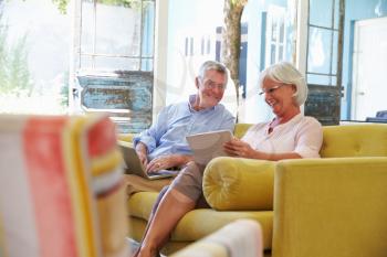 Senior Couple At Home In Lounge Using Digital Devices