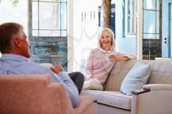 Mature Couple At Home Relaxing In Lounge With Hot Drink