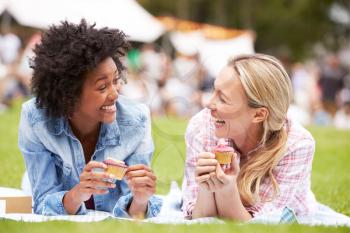 Two Female Friends Enjoying Cupcakes At Outdoor Summer Event