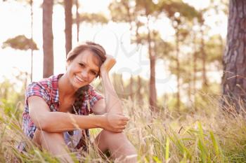 Portrait Of Smiling Young Woman Sitting In Countryside