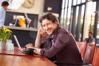 Man working on computer at coffee shop, portrait
