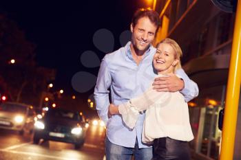Couple embracing on city street at night, portrait