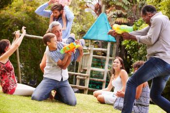 Adults and kids having fun with water pistols in a garden