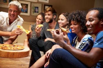 Friends eating pizza at a house party, watching television