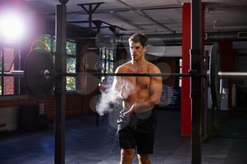 Bare Chested Man In Gym Preparing To Lift Weights
