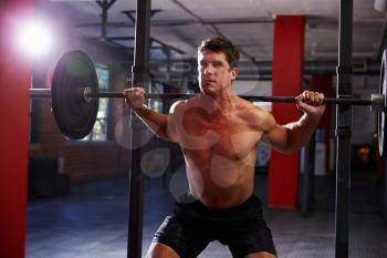 Bare Chested Man In Gym Lifting Weights