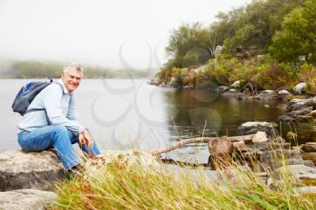 Smiling senior man sitting by a lake