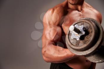 Male bodybuilder working out with a  heavy dumbbell, crop detail