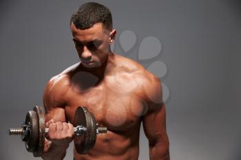Muscular young man working out with a heavy dumbbell